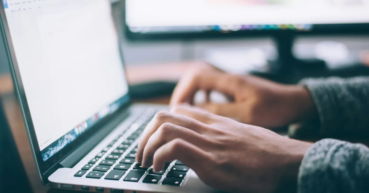Hands typing on a laptop keyboard at a desk