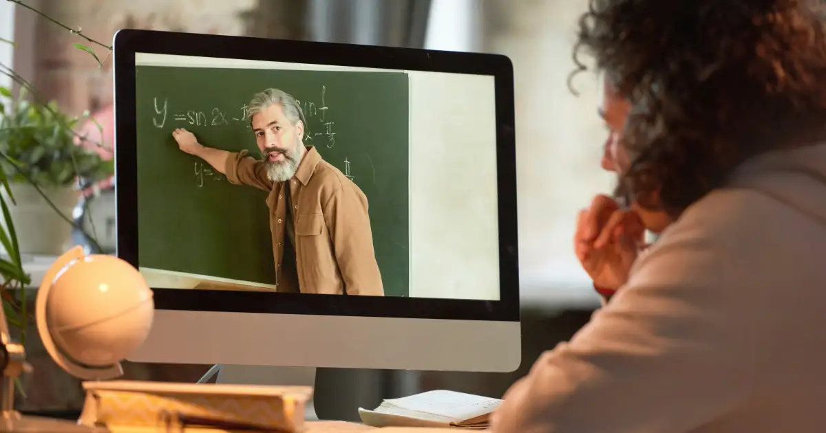 Learner watching an online lesson video with notes beside the laptop